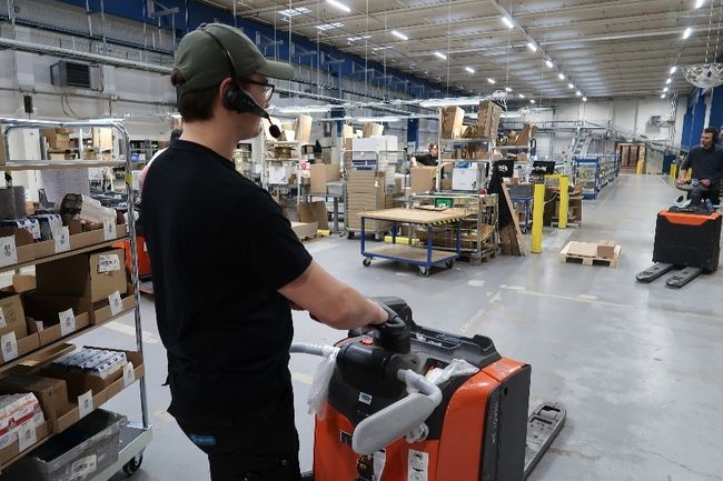 Equipés d'un terminal mobile vocal et d'un casque, les opérateurs reçoivent des instructions de picking en temps réel et peuvent travailler les mains libres<br>
                              Crédit photo : Zetes